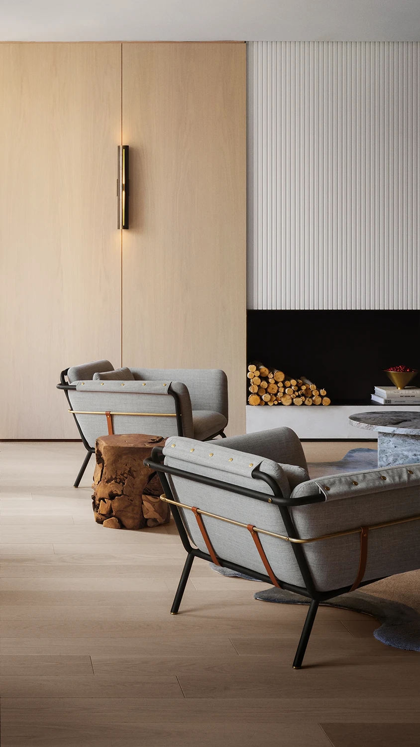 A lounge area with a tree stump as a side table to plush grey lounge chairs