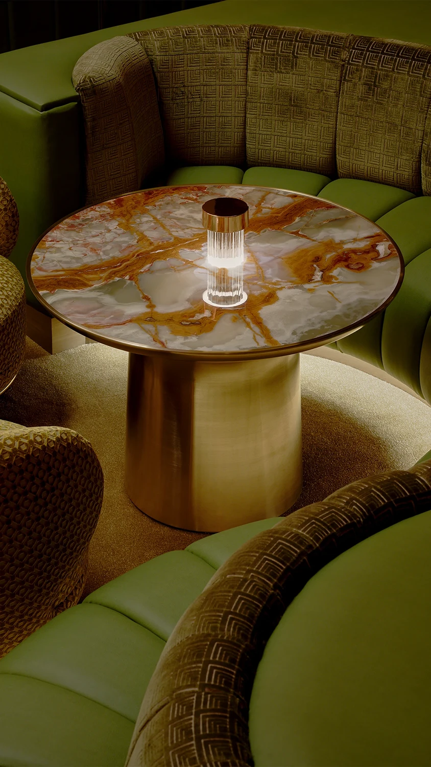 A green leather couch surrounding a small marble circle table with a single light
