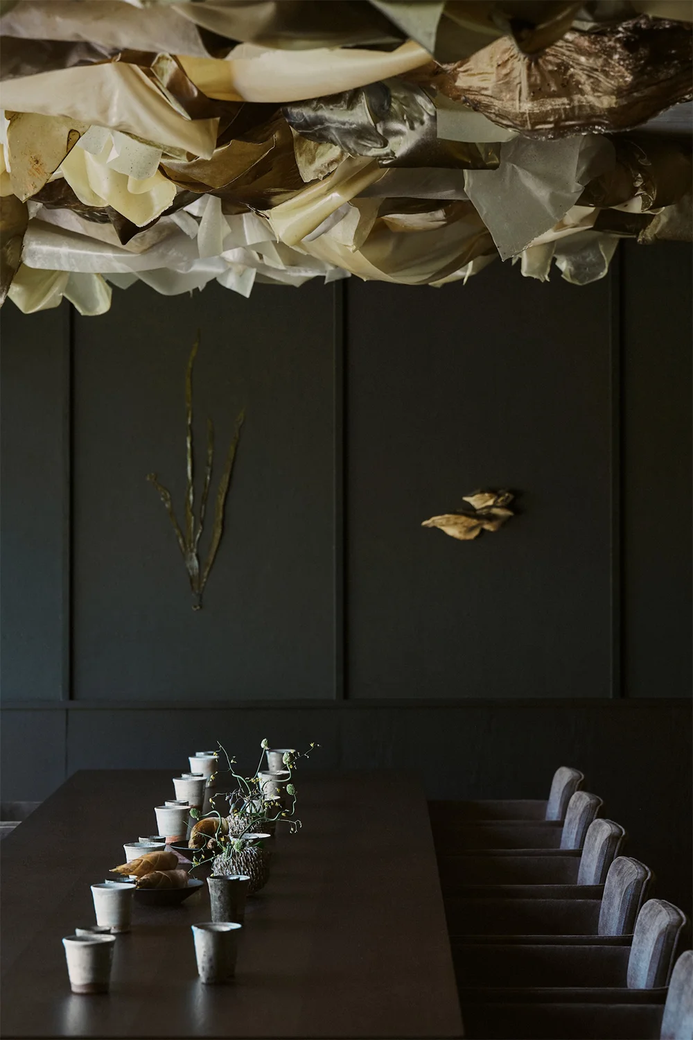A table set with cups and lines of chairs lit by a unique contemporary chandelier