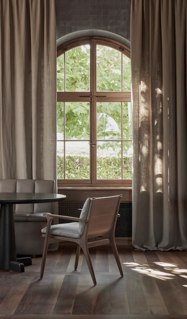 Wooden half-moon arch-topped window lights up lounging area with a wooden desk, and bespoke chair.
